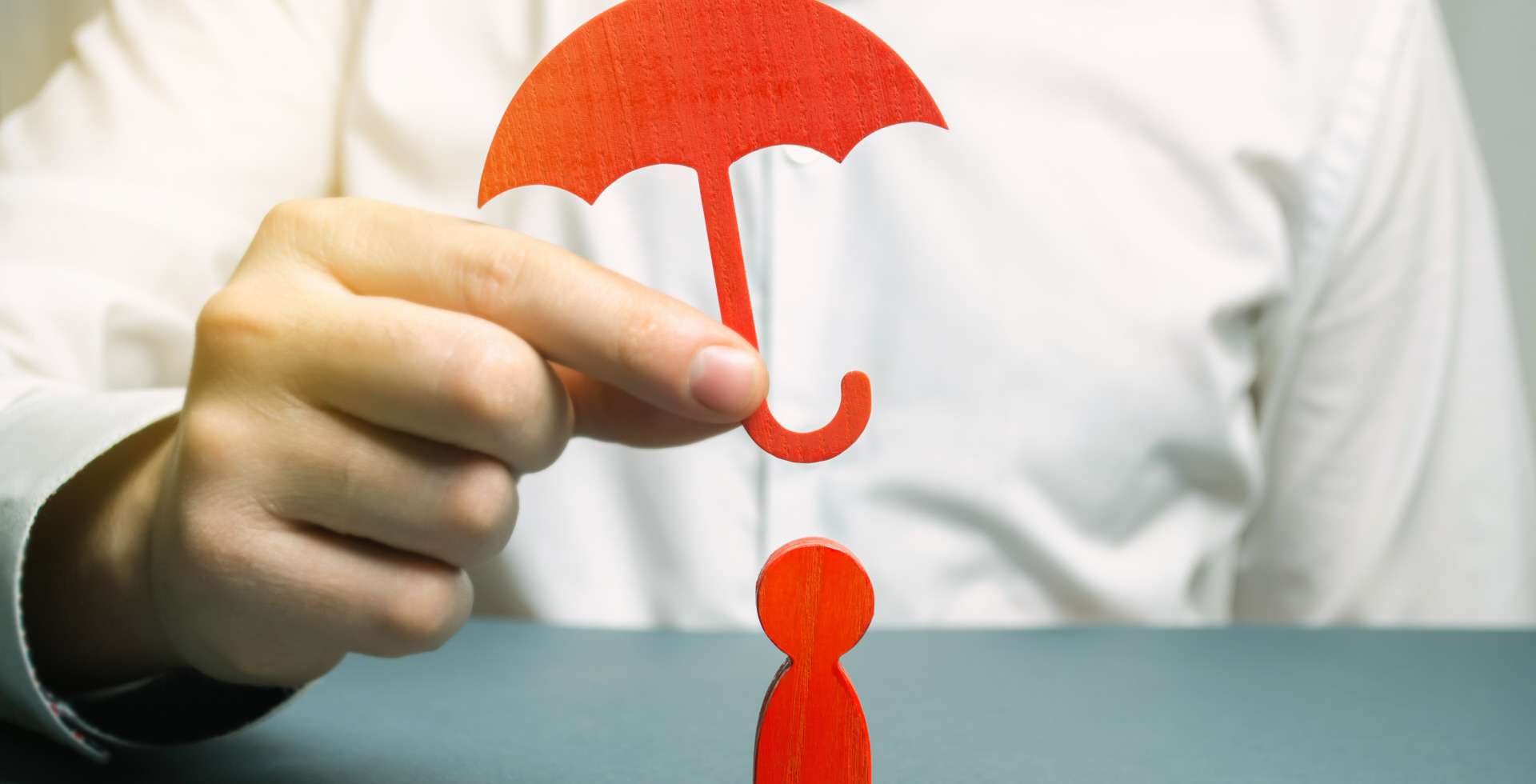 Man holding red umbrella over wooden figure