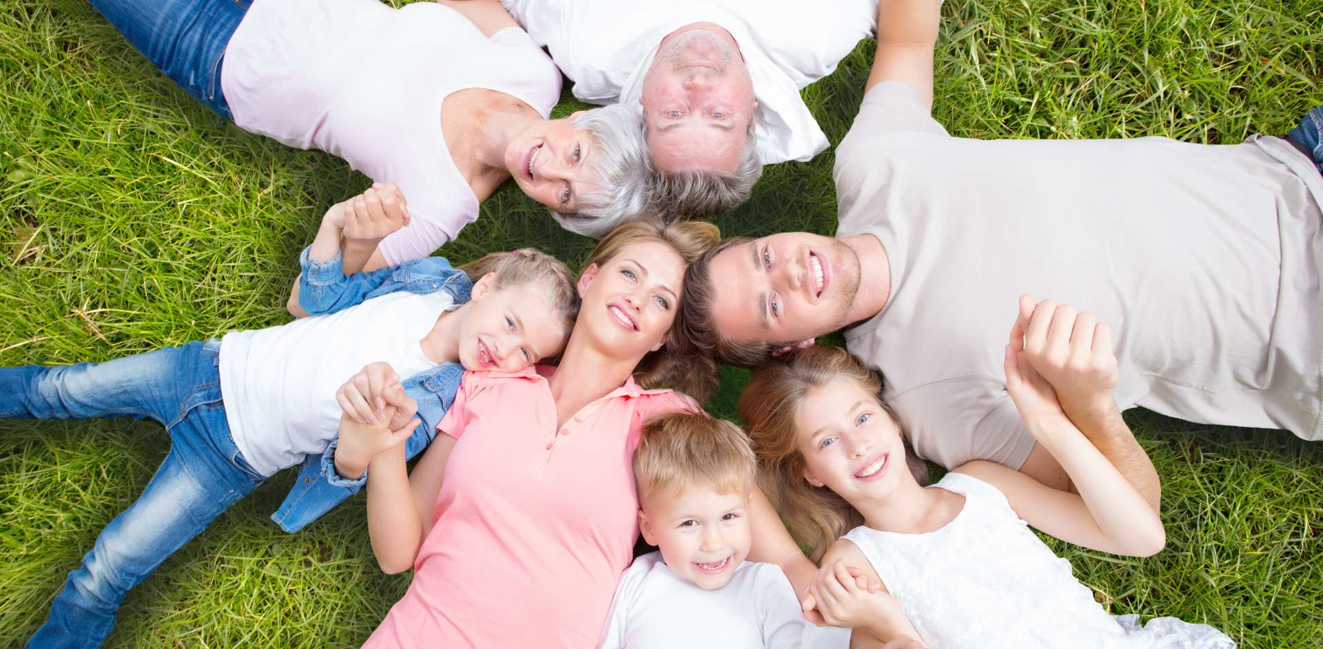 Family Lying in circle heads together on grass